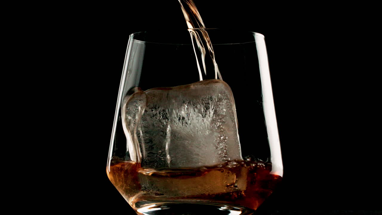 Whiskey being poured into a glass with ice