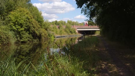 wide shot of british countryside with trent and mersey canal with the a 50 due carriageway bridge in distance