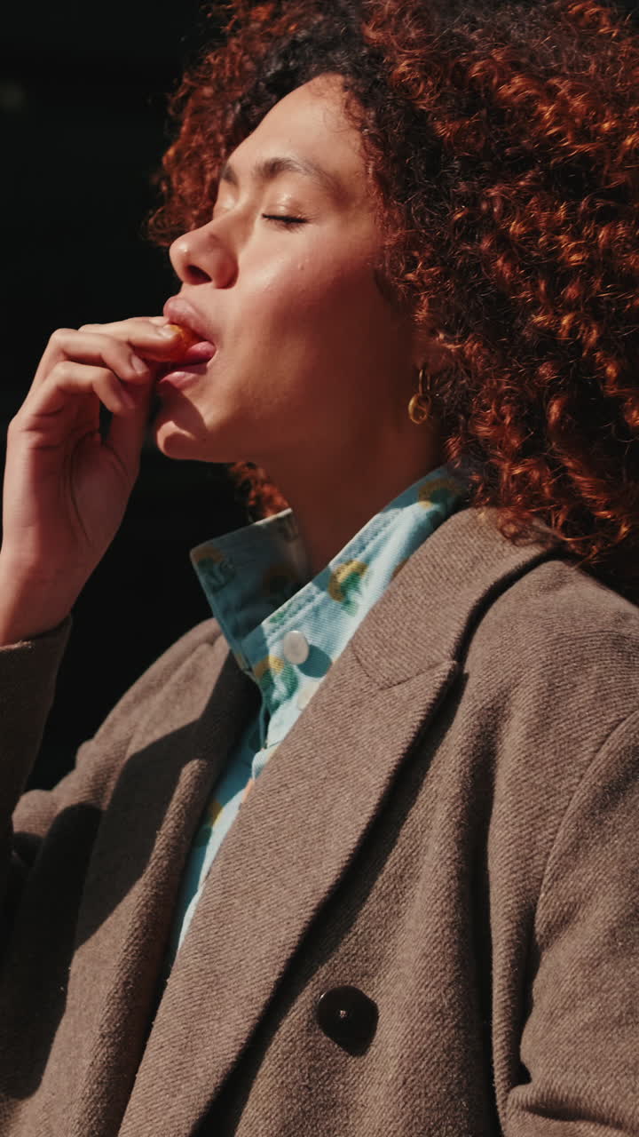 Young Woman Eats Orange Slice in City