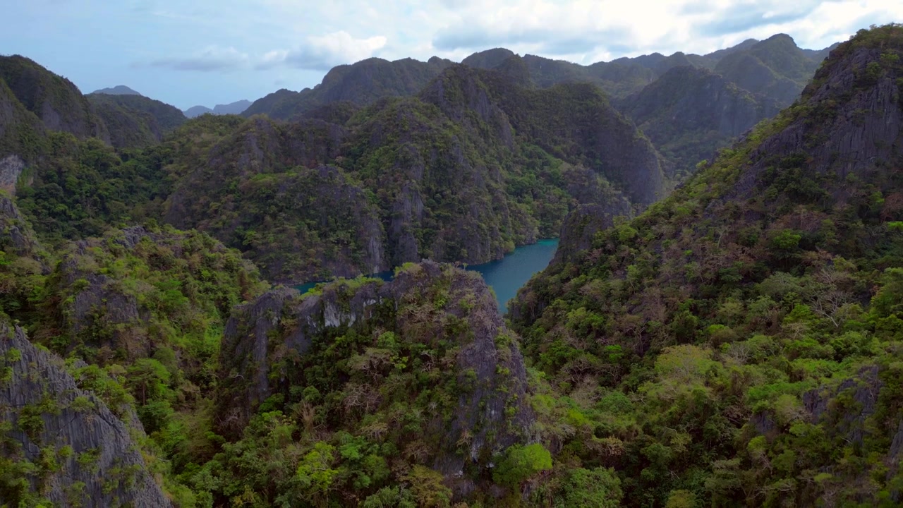 Filipinler'deki Coron Adası'nda bulunan Kayangan Gölü'nün sakin mavi sularını çevreleyen kireçtaşı kayalıkları. Güzel havadan görünüm, alçalan drone panoraması.