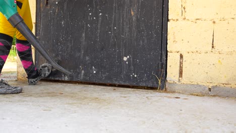 low angle view of a worker using a blower to move straw into a stall and closing the door