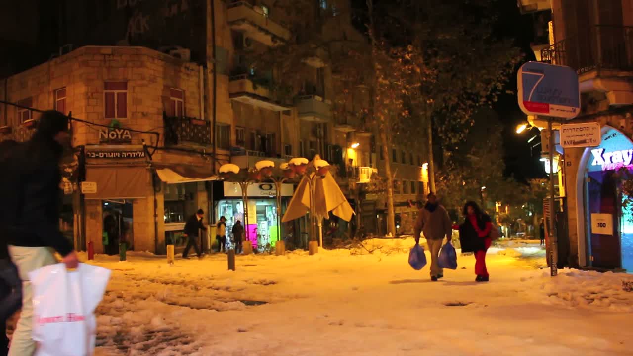사람들은 밤에 예루살렘의 노야 레스토랑을 지나 비정상적으로 눈 덮인 거리를 걷는다
