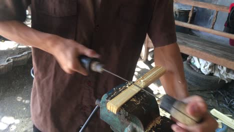 artisan crafting bamboo strips with hand tools and a vice