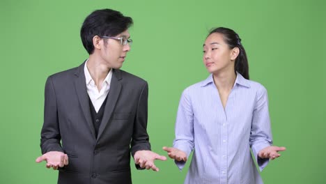 young asian business couple shrugging together