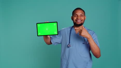 Portrait-of-joyous-male-nurse-pointing-finger-towards-isolated-screen-tablet