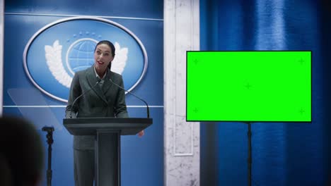 organization female representative speaking at press conference in government building with green screen mock up on display. press officer delivering a speech at summit. minister in congress.