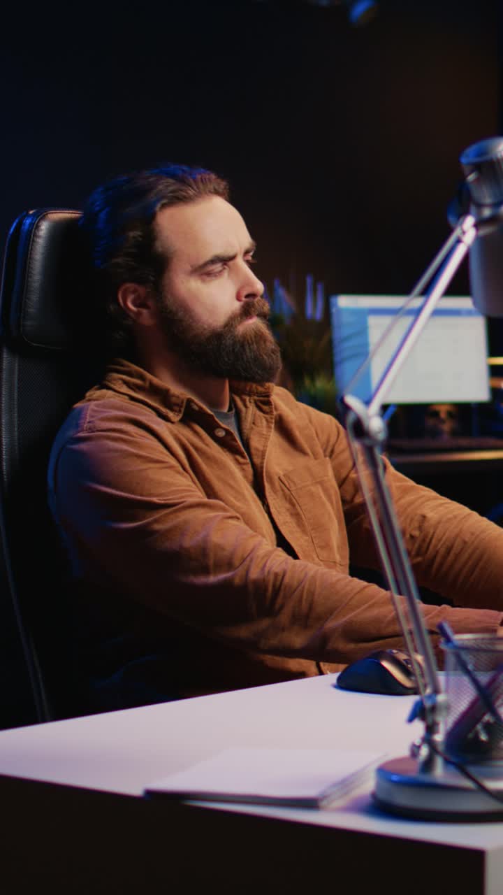 Focused Man Working on Computer Late at Night in Dark Office