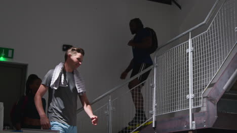 male and female athletes in fitness clothing training in gym walking down stairs to changing rooms before or after exercise 2