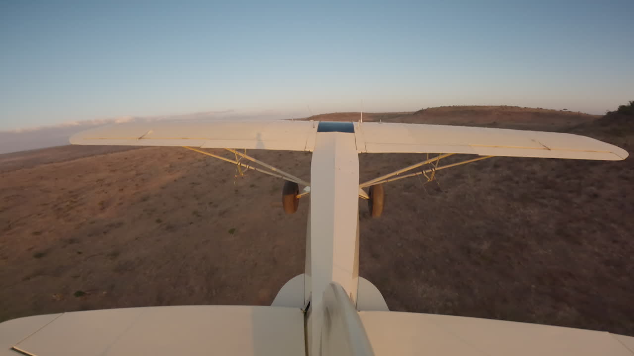 Aereo da boscaglia che vola su pianure aride in Kenya al tramonto