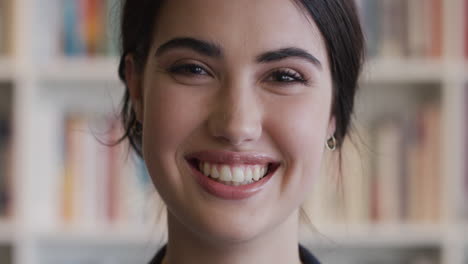 Portrait-beautiful-woman-student-smiling-in-front-of-bookshelf-happy-to-be-in-university