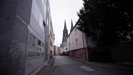 a quiet street in cologne leads the eye to the iconic twin spires of the cologne cathedral, rising above the urban landscape like a timeless monument.