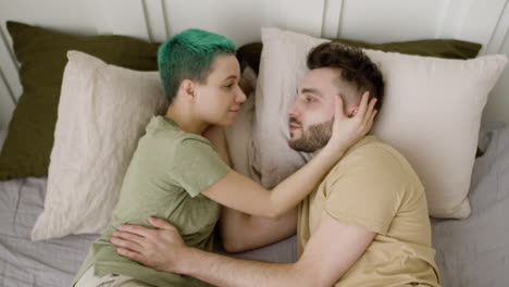 Top-View-Of-A-Loving-Couple-Talking-And-Looking-At-Each-Other-While-Lying-On-The-Bed