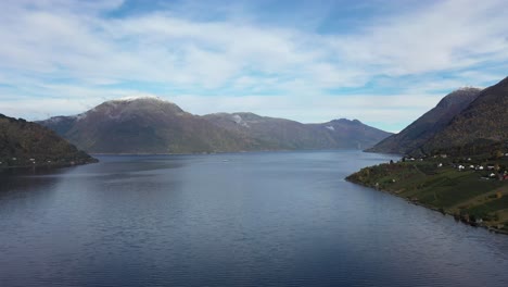 Sorfjorden-in-Hardanger-with-Utne-at-left-side-with-Ferry-Kinsarvik-in-middle-and-Hardanger-bridge-in-far-background---Beautiful-sunny-day-autumn-aerial---Norway