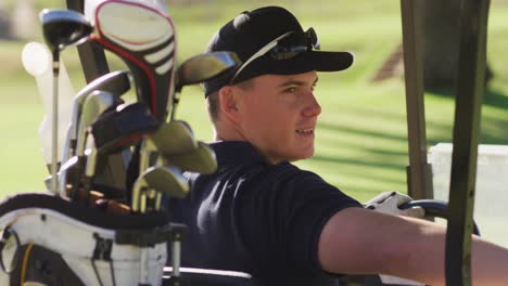 video of happy caucasian man sitting in cart on golf field