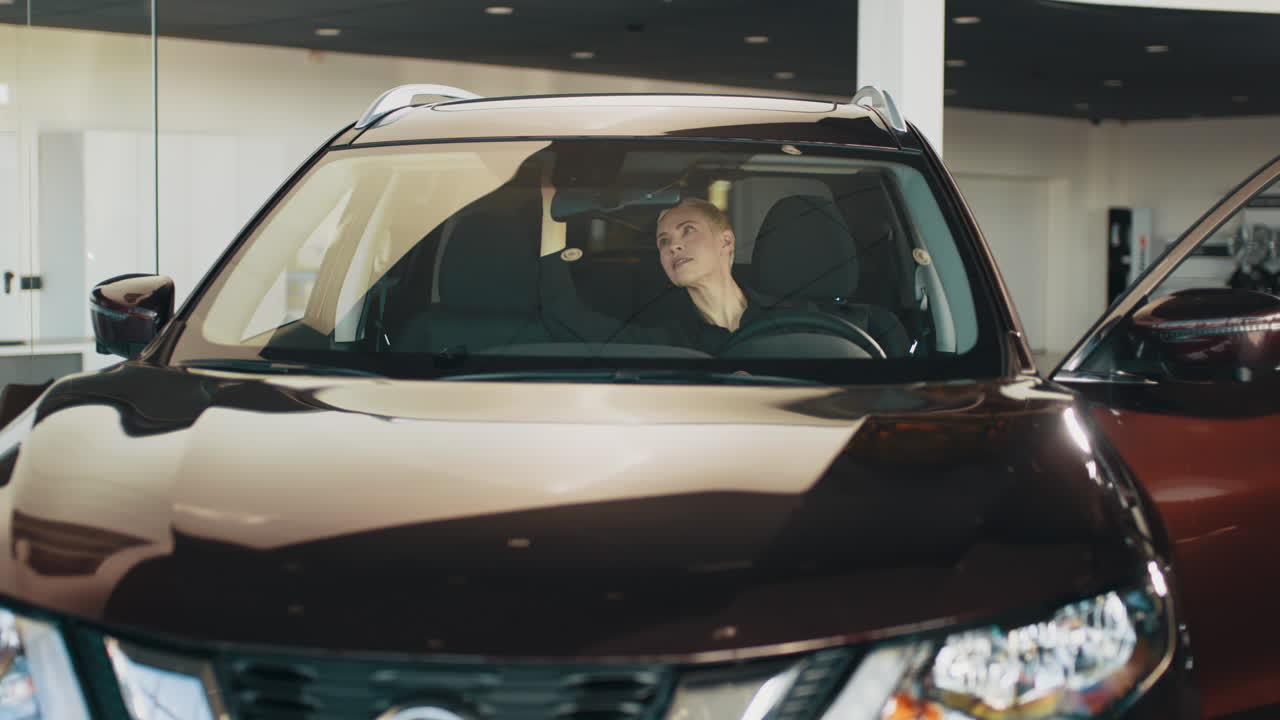 mujer mirando un coche en la sala de exposiciones