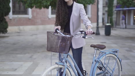 woman with curly hair riding a light blue bicycle