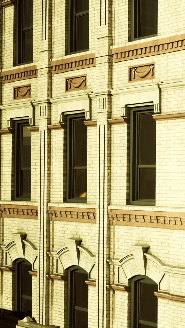Esterno di un edificio con finestre e dettagli architettonici sotto la luce del sole.