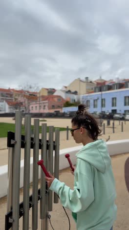 woman playing tubular bells in a city park