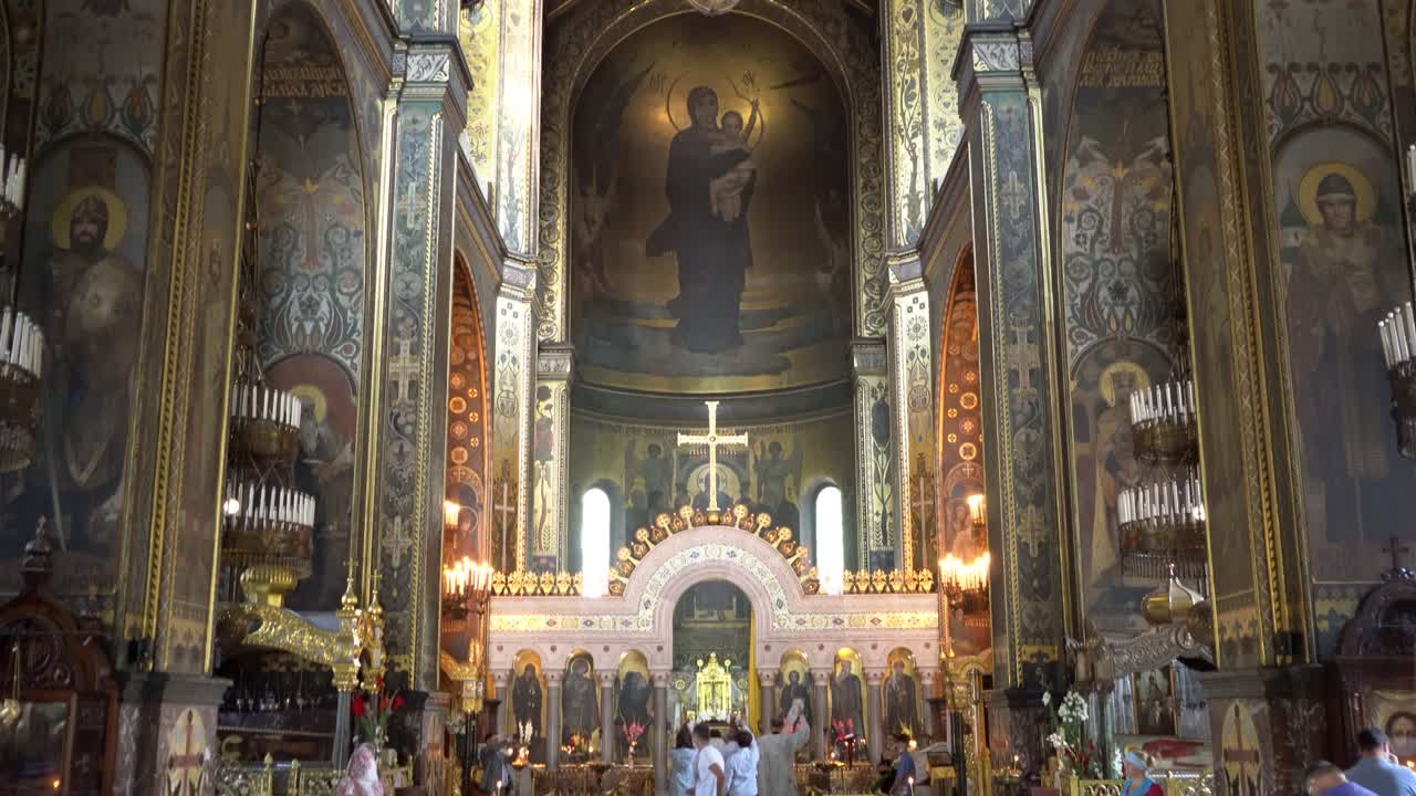 Ukraine,Kyiv,St Volodymyr Cathedral's beautifully decorated interior, main apses of the Church from bottom to top, camera tilts up slowly, people walking, standing and praying at the main area.