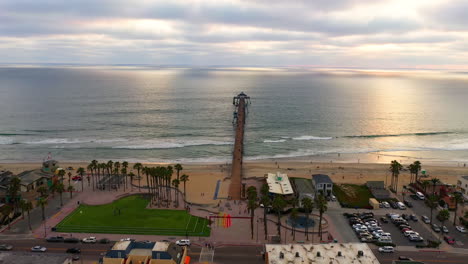 vista aérea de personas paseando tranquilamente en la playa imperial con un muelle que se extiende sobre el océano pacífico al atardecer