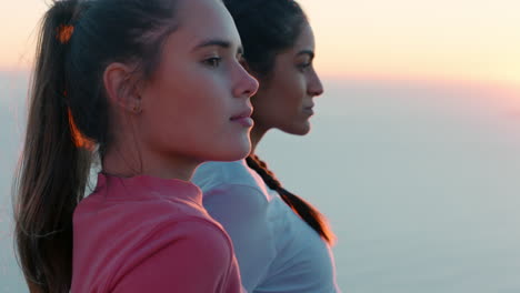 best friends sitting on mountain top looking at view of ocean at sunset two women resting after hike enjoying peaceful outdoors travel adventure