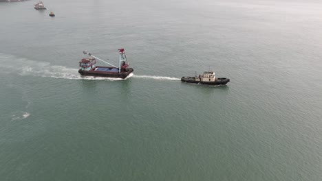 remolcador tirando de una pequeña barcaza en la bahía de hong kong, vista aérea
