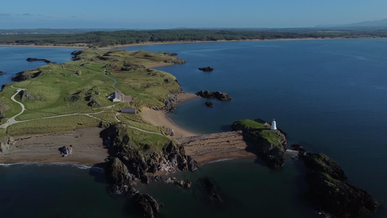Aerial view looking down Ynys Llanddwyn island at sunrise with coastal lighthouse