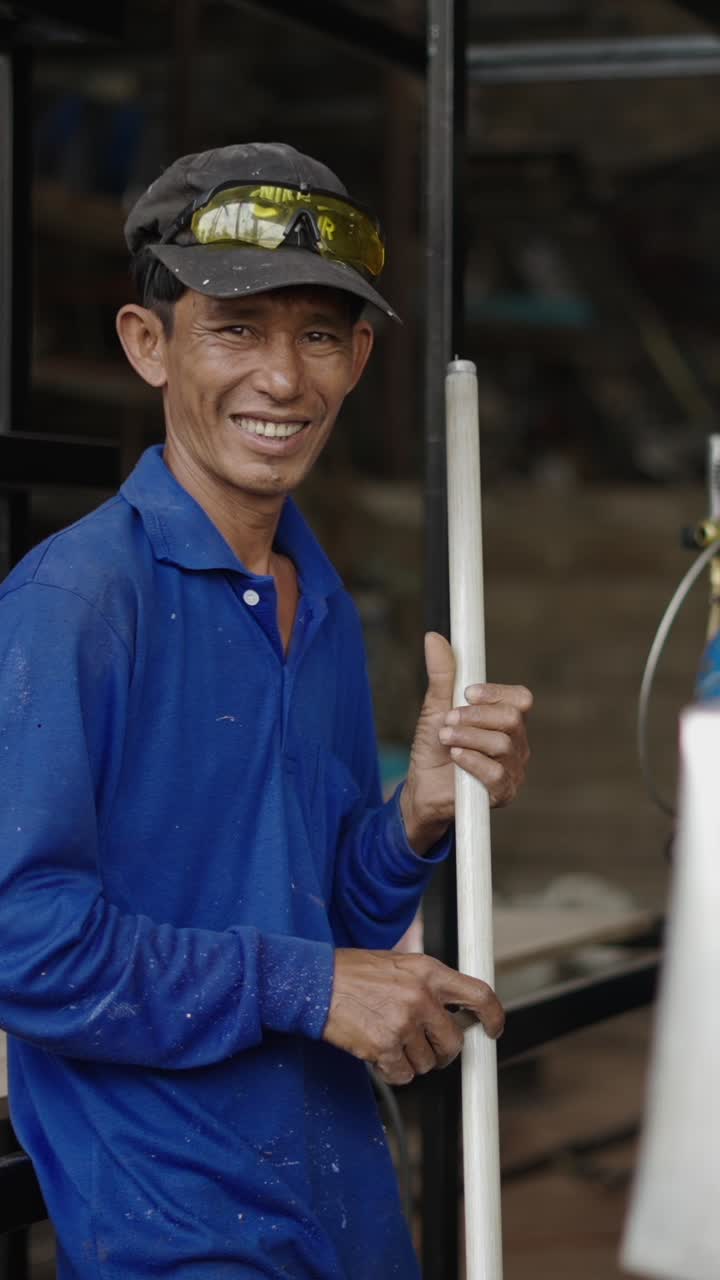 Smiling man in blue shirt and cap holding a pole