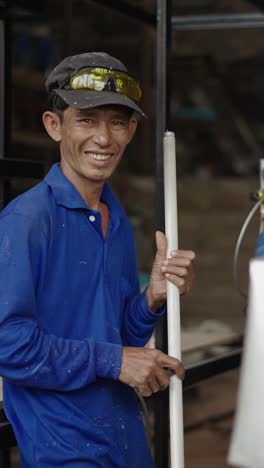 smiling man in blue shirt and cap holding a pole