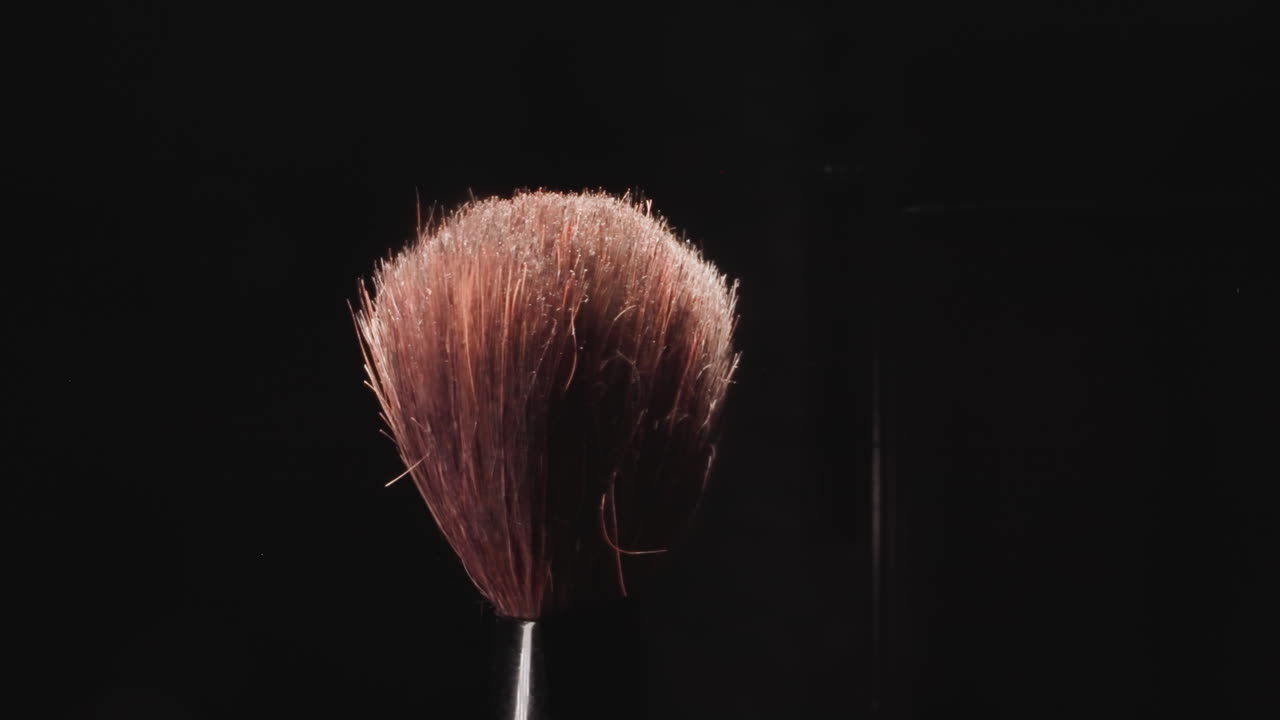 Old makeup brush with long hard bristles on black background