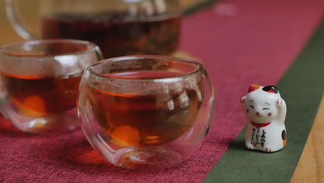 a cup of tea with a cute maneki-neko figurine