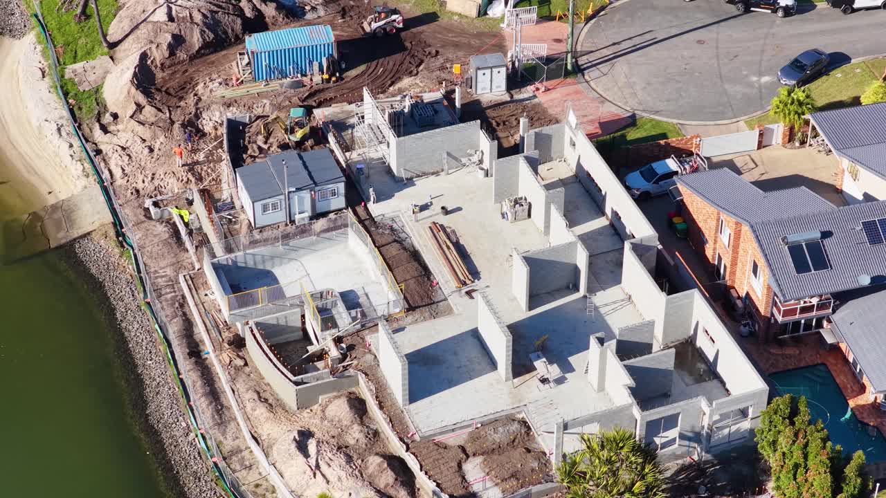 Drone footage captures a construction site near a water canal in Gold Coast, Australia, highlighting ongoing building activities