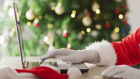 santa claus usando una computadora portátil sobre el árbol de navidad y las luces