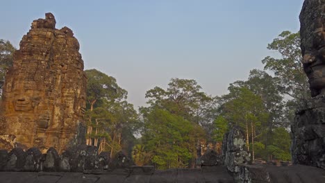 giant stone faces at bayon temple at sunset