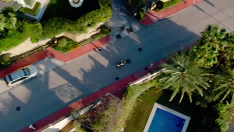 person driving through luxury home area on motorbike in aerial view