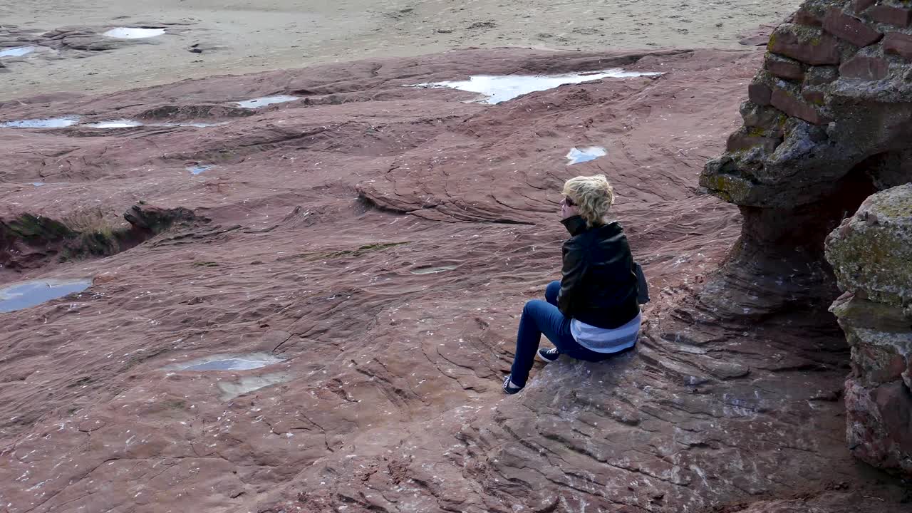 아름 다운 젊은 여자는 wirral 반도에서 hilbre 언덕에 앉아