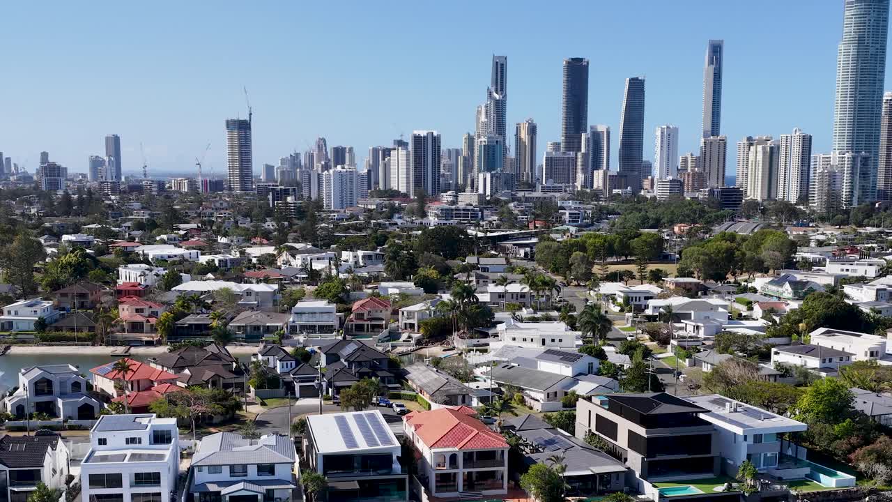 Drone glides over canal houses toward modern skyscrapers, bright daylight, clear blue sky, smooth motion