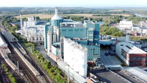 industrial chemical manufacturing factory next to warrington bank quay train tracks aerial view descending shot