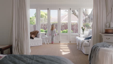 cute little girl in bedroom looking out window enjoying beautiful weekend morning at home wearing pajamas