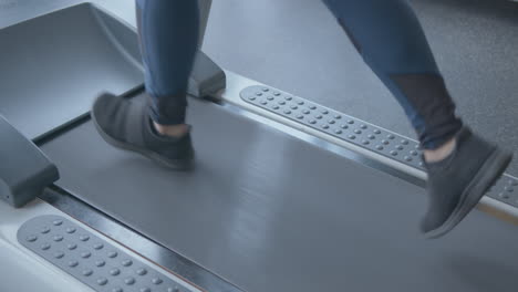 cerrar la cámara lenta de las piernas de una mujer trotando en una caminadora