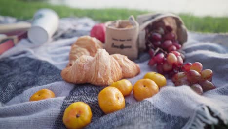 picnic romántico para dos con manzanas, uvas, mandarinas, café y croissants en la playa