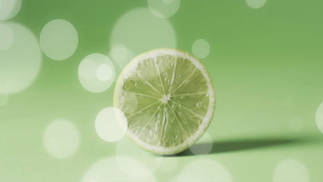 composition of halved lime over white spots of light on green background