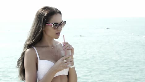 beautiful girl drinks mojito cocktail on the background of the sea