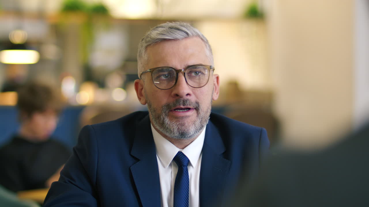 Mature Businessman Speaking with Colleague during Meeting at Restaurant