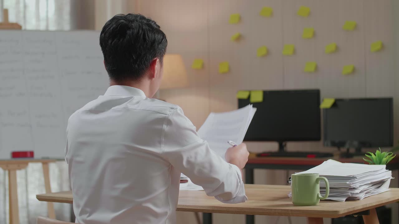 Back View Of Happy Asian Man Celebrating Finishing Working With Documents At The Office