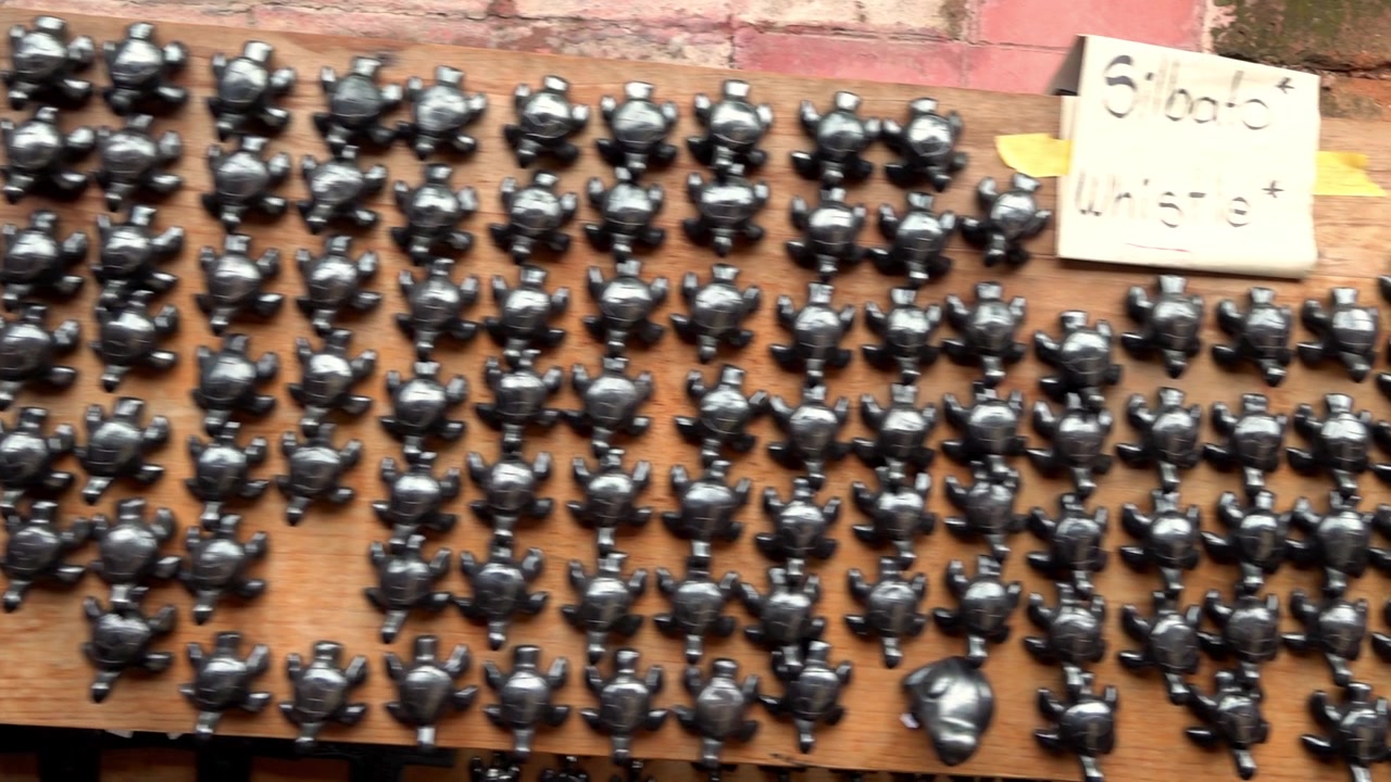 Collection of handcrafted turtle figurines displayed in organized rows on wooden table inside traditional artisan market in Mexico