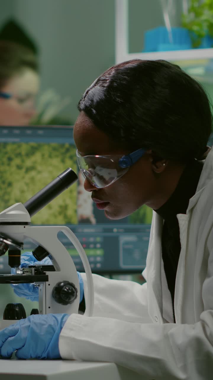 Female scientist observing samples with a microscope in a research ...