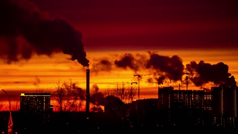 ciudad moderna por la noche al atardecer. el humo sale de las tuberías.