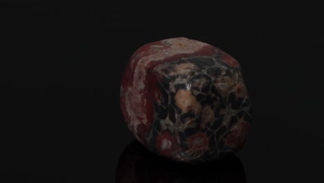 detailed view of a jasper stone rotating, showcasing its unique patterns and colors against a dark background.