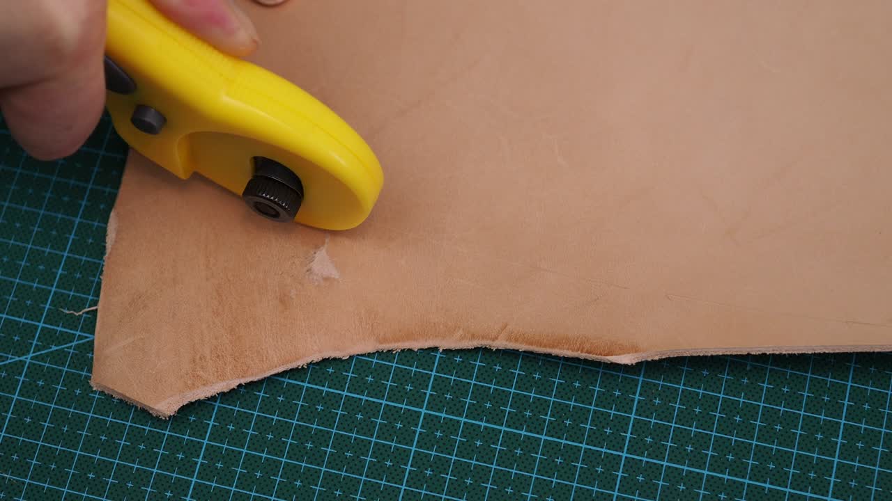 craftsman cuts details of handbag from  leather by rotary cutter knife